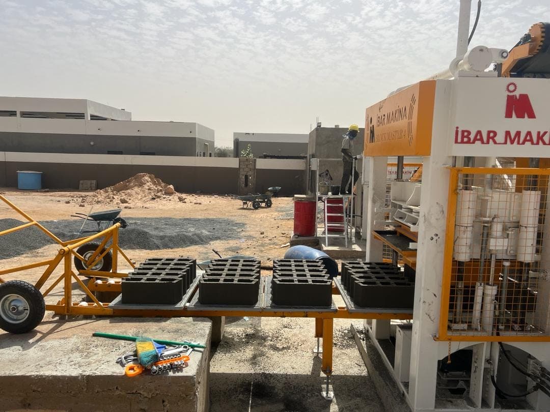 Pallet trolley beside the BLOCKMASTER 4 loaded with pallets of four hollow concrete blocks each (20 cm block mould), Senegal