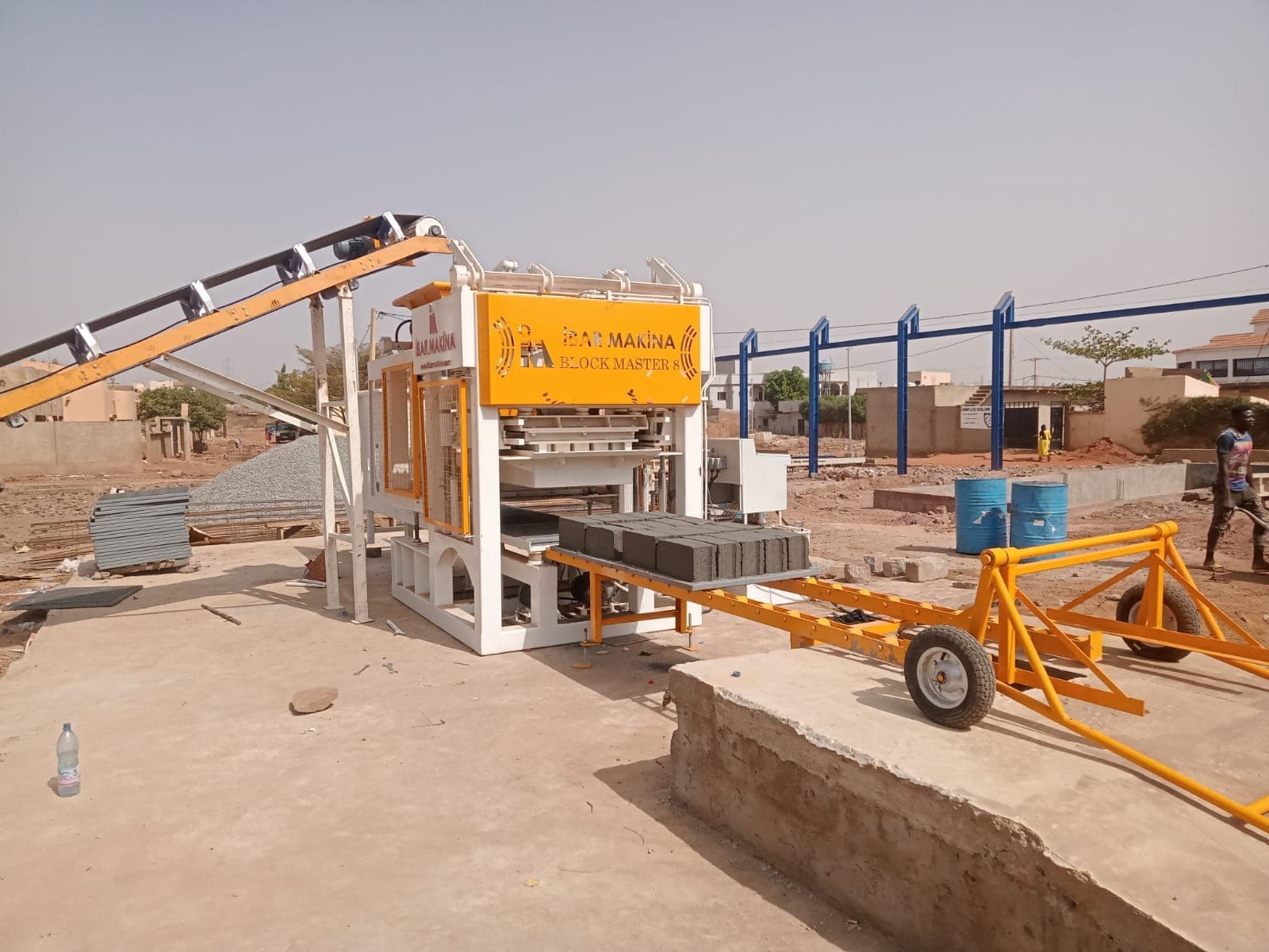 BLOCKMASTER 8 with belt conveyor feed and pallet trolley at the raised loading edge, Bamako