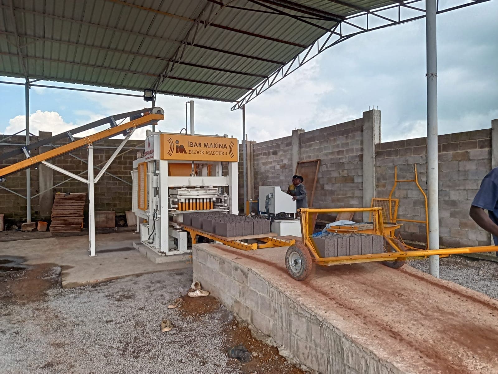 BLOCKMASTER 4 block making machine under a steel roof in Kolwezi with belt conveyor and pallet trolley, DR Congo