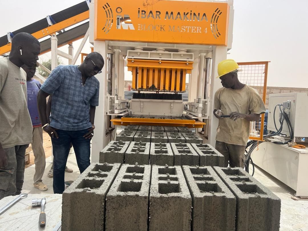 Team inspecting one of the first pallets in front of the BLOCKMASTER 4 block machine, Senegal