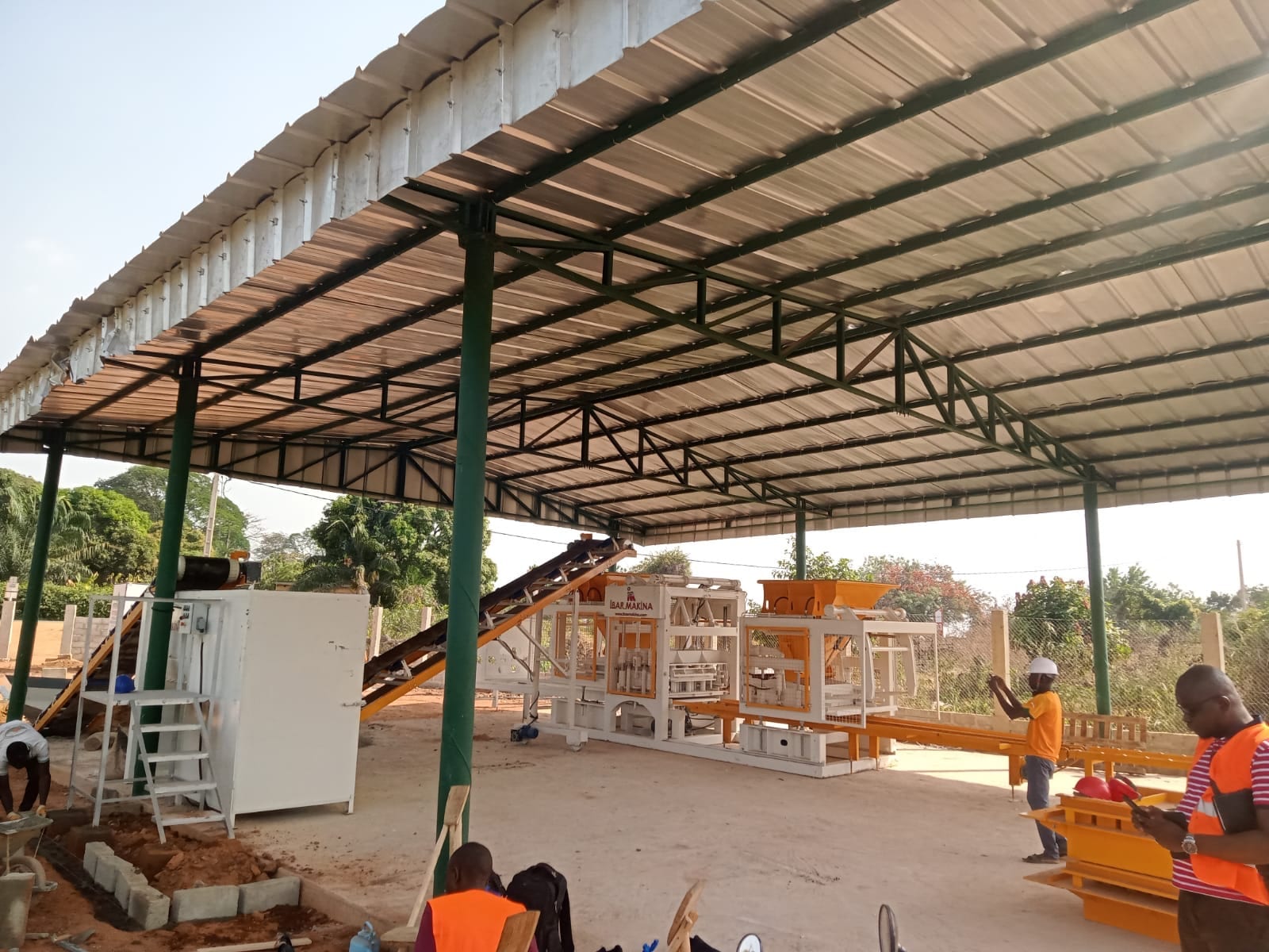 Machine à parpaings CBM 25 avec malaxeur et convoyeur sous le hangar de production à Bouaké